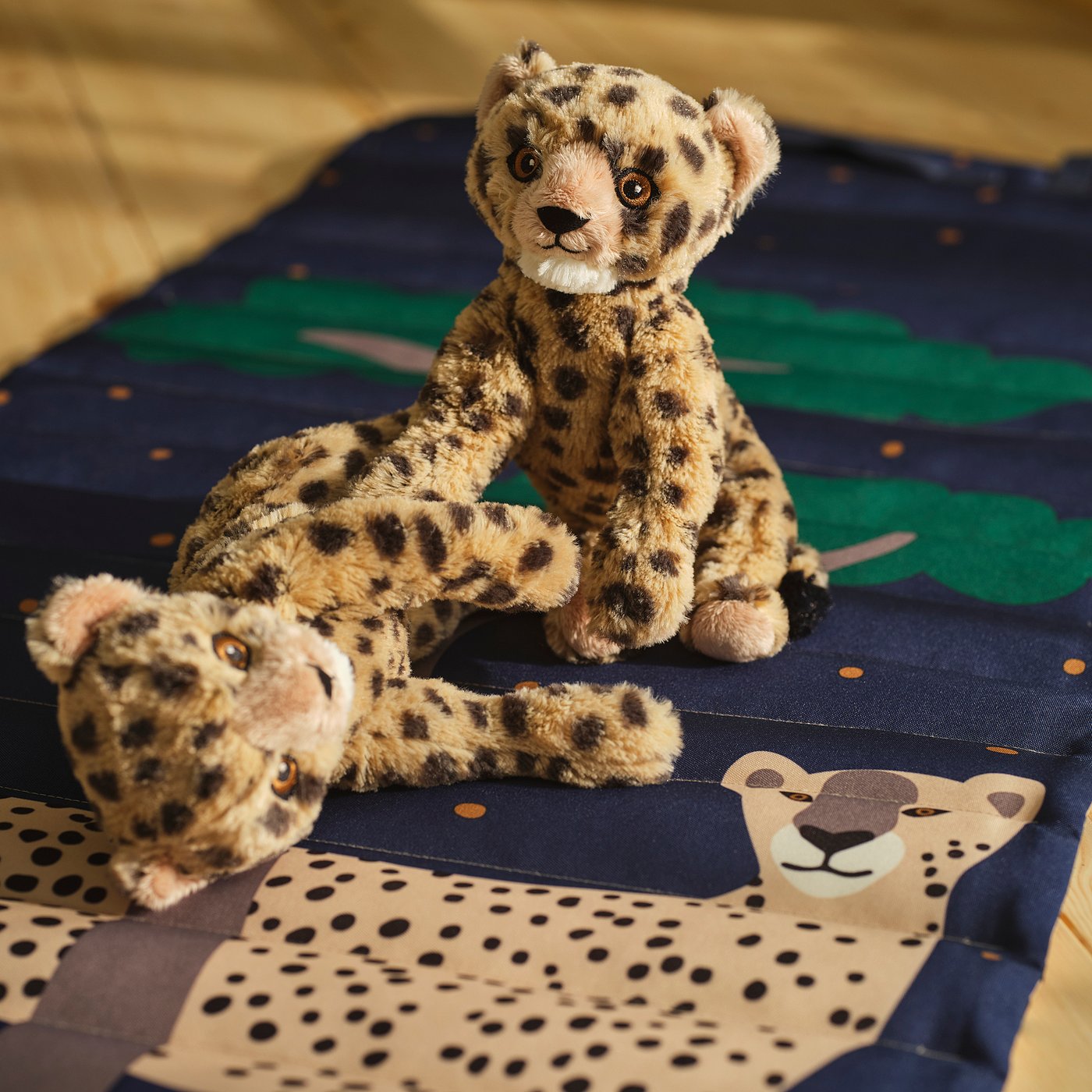 Deux jouets en peluche guépard sur une couverture rayée ; l’un debout, l’autre couché. Textures réalistes, environ 10 pouces chacune.
