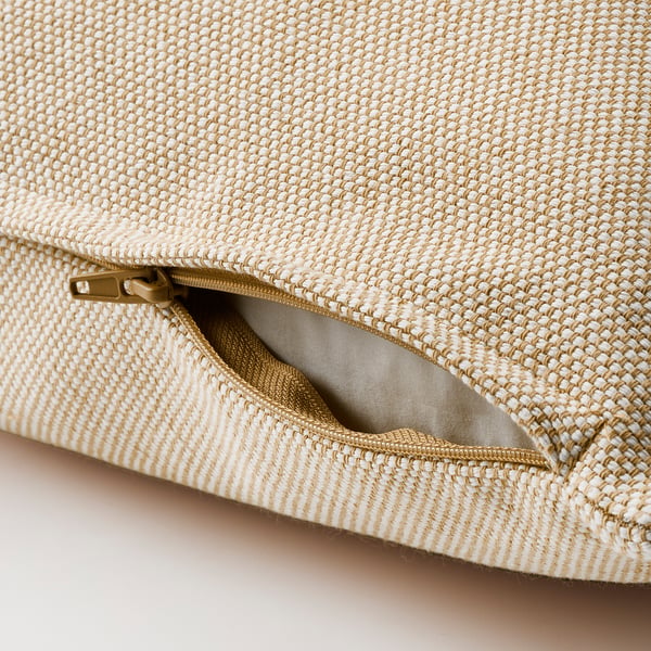 Coussin beige avec tissu texturé, fermeture éclair ouverte dévoilant la doublure intérieure.