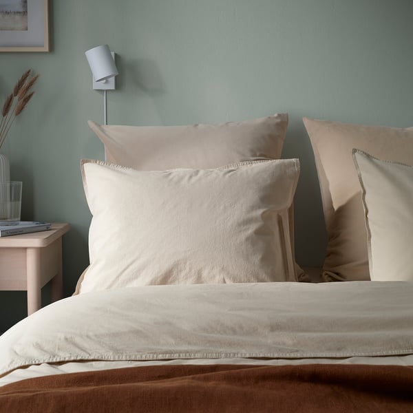 Coussin en velours beige sur le lit ; doux, élégant avec fermeture éclair ; Mur vert, lumière blanche.