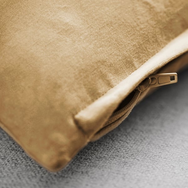 Gros plan d’une luxueuse housse de coussin en velours beige avec tirette de fermeture éclair faisant allusion à un tissu et à un savoir-faire de haute qualité.
