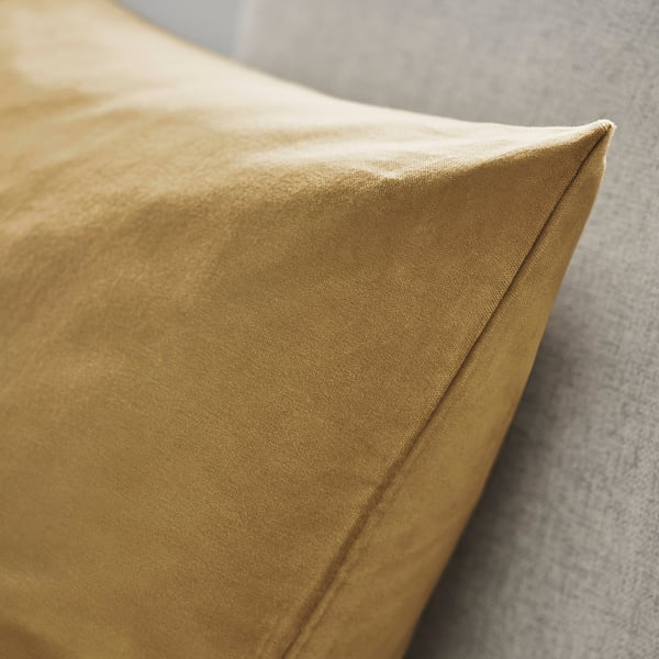 Gros plan sur la housse de coussin en velours de coton jaune moutarde, mettant en valeur sa texture lisse et ses coutures soignées.