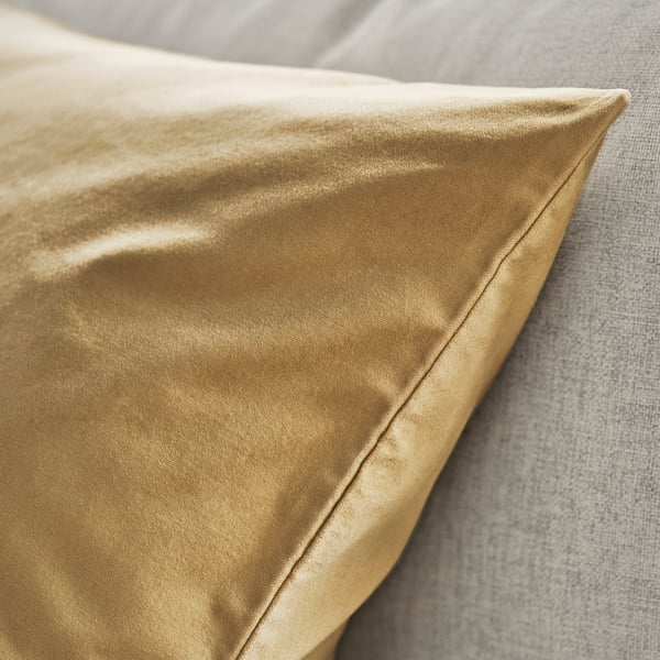Housse de coussin en velours doré avec une texture lisse et luxueuse et un éclat subtil.