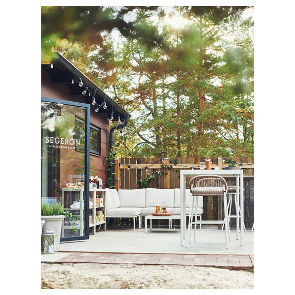 Sièges d’extérieur modernes avec mobilier SEGERÖN près du bâtiment, verdure, éclairage chaleureux.