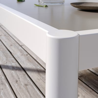 Une table d’extérieur blanche et moderne avec des pieds cylindriques. Fabriqué en aluminium et en acier thermolaqué, parfaitement adapté aux patios.