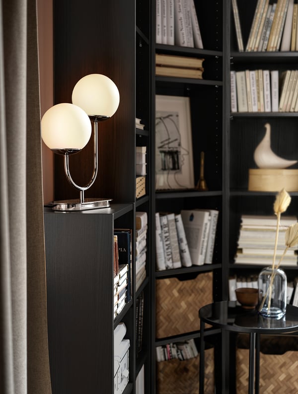 Lampe moderne avec deux globes en verre blanc sur étagère noire.