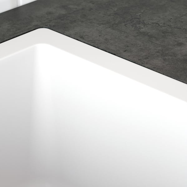 Évier blanc élégant aux bords lisses, au design minimaliste et aux lignes épurées, le tout sur un comptoir gris texturé.