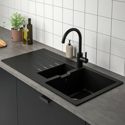 Évier de cuisine moderne avec robinet noir et égouttoir réversible.