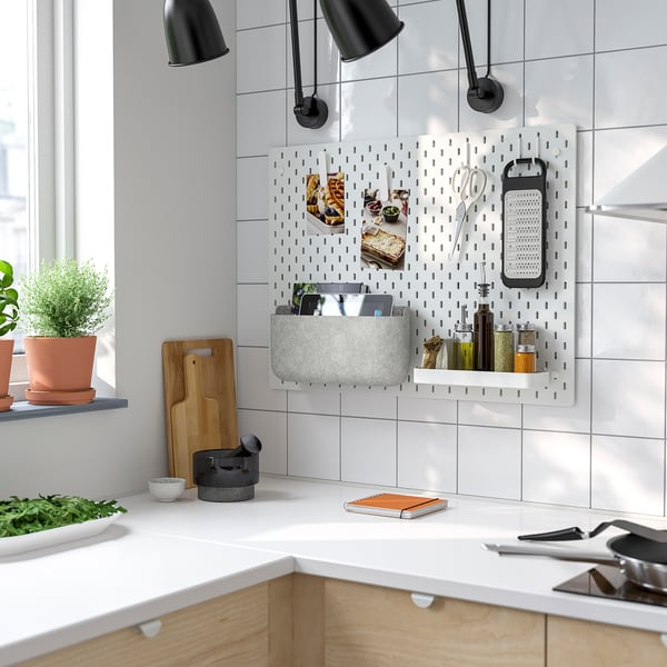 Cuisine moderne avec panneau perforé SKÅDIS contenant des paniers, des bouteilles et des ustensiles gris.