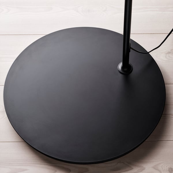Base de lampadaire ronde noire avec finition lisse et design circulaire sur sol en bois.