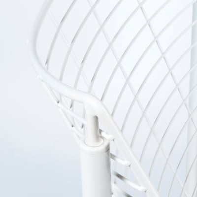 Gros plan du dossier d’une chaise en métal blanc, mettant en valeur son motif en treillis complexe et incurvé et ses articulations robustes.