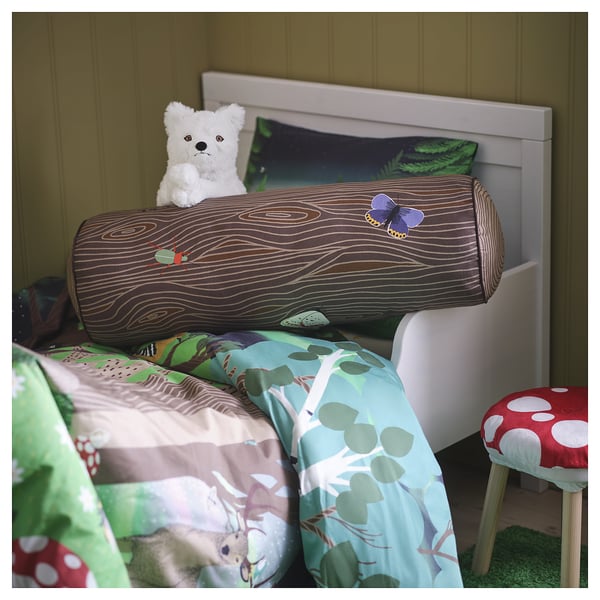 SKOGSDUVA : oreiller en forme de tronc d’arbre avec des insectes sur le lit, mur blanc.