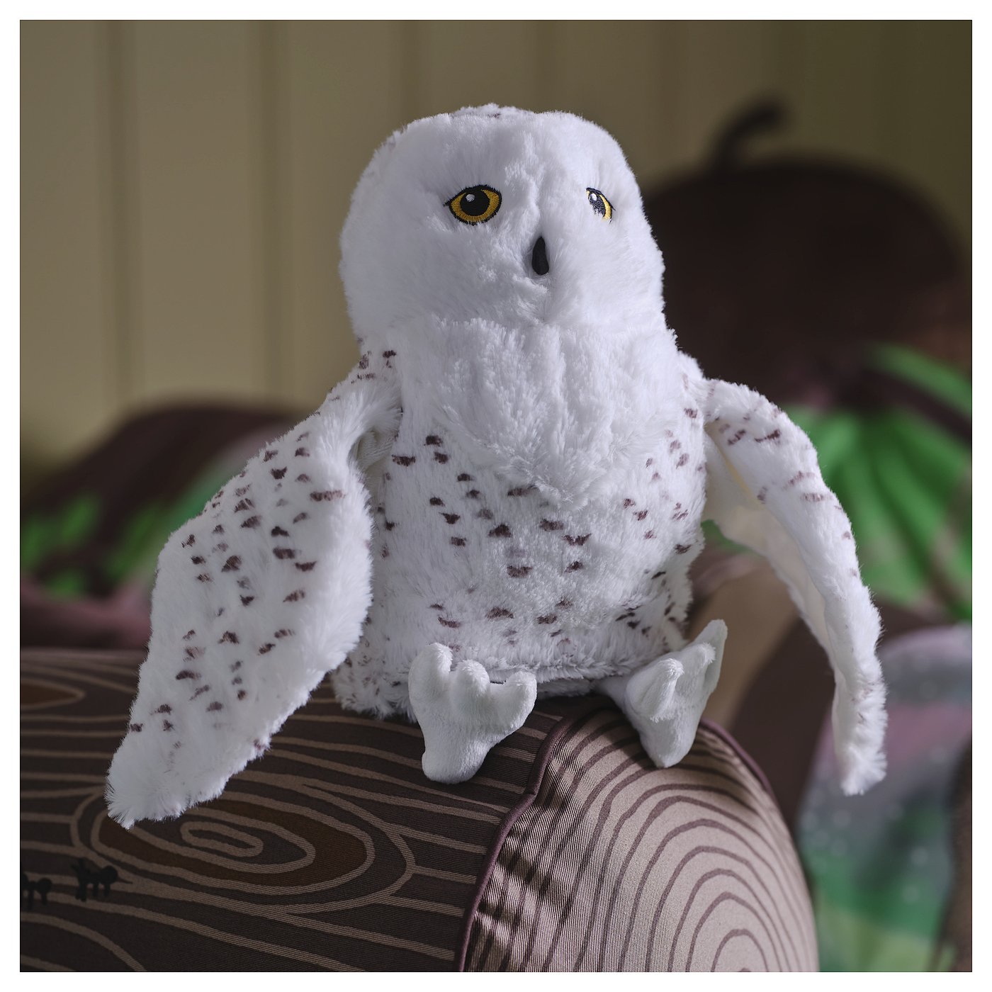 Le hibou SKOGSDUVA blanc doux repose sur un coussin. Grands yeux ronds, petites taches brunes. Taille similaire à celle d’une main.