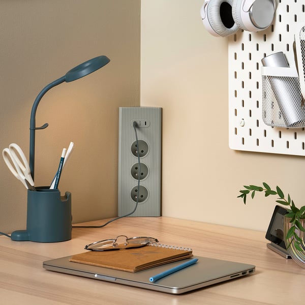 Rallonge bleue sur bureau en bois avec lampe, ordinateur portable et plante. Design minimaliste.