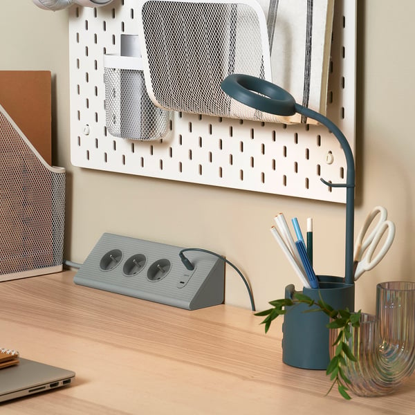 Configuration de bureau moderne avec rallonge SKOTAT, multiprise et usb, et lampe à col de cygne bleue.