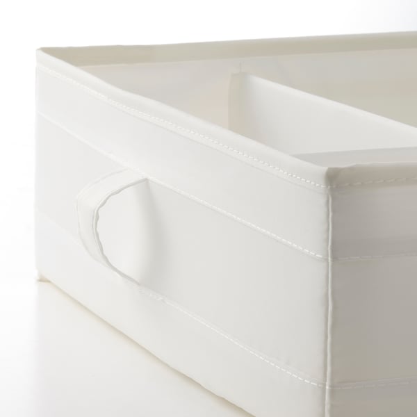 Gros plan de la boîte de rangement en tissu blanc avec coutures renforcées et poignées latérales, conçue pour être peu encombrante.