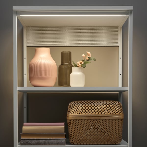 Étagère moderne avec lumières LED, vases et panier.