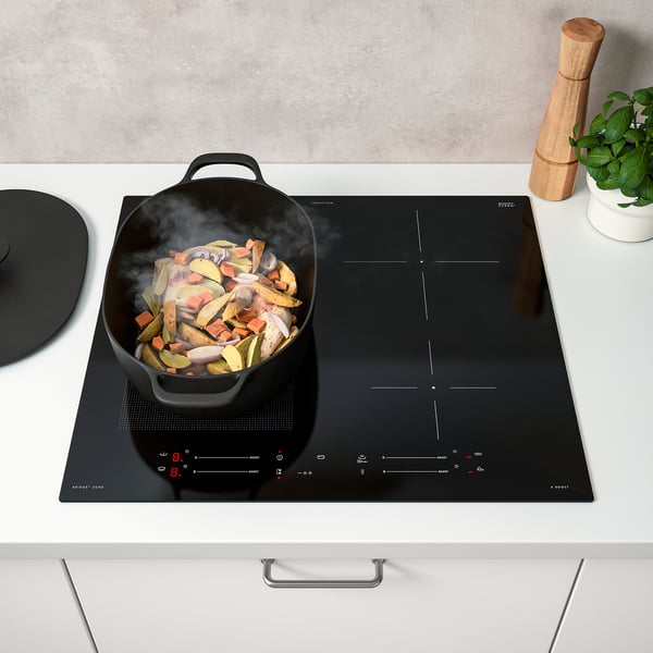 Scène de cuisine moderne avec une poêle à vapeur sur une cuisinière à induction, montrant l’augmentation de puissance et les fonctions de pont.