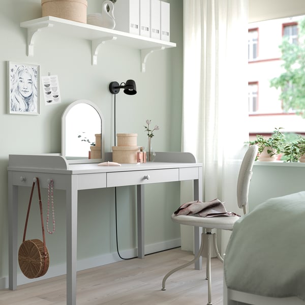 Chambre moderne avec bureau SMYGA, chaise, miroir et étagères. Décoré d’œuvres d’art, de plantes et d’un sac ; Lumière naturelle d’une grande fenêtre.