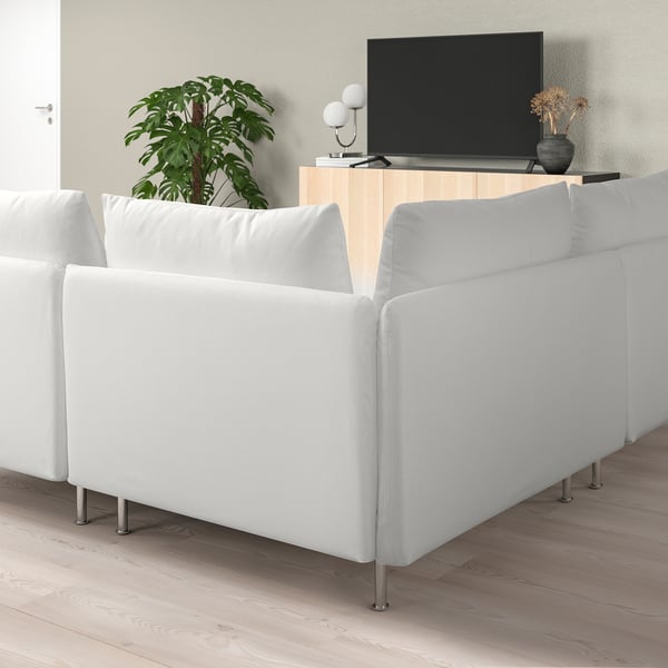 Canapé sectionnel blanc moderne dans un salon minimaliste avec télévision et plante.