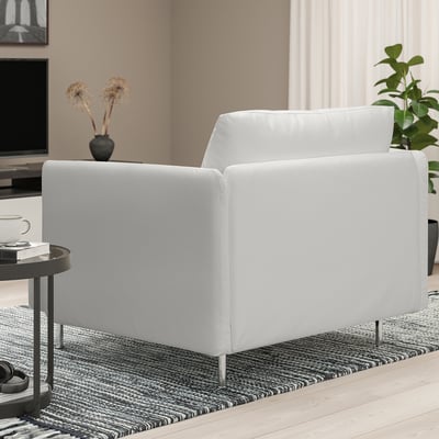 Salon minimaliste moderne : grand fauteuil SÖDERHAMN blanc sur tapis, à côté d’une petite table avec tasse, livres et vase, près de la télévision et de la plante.