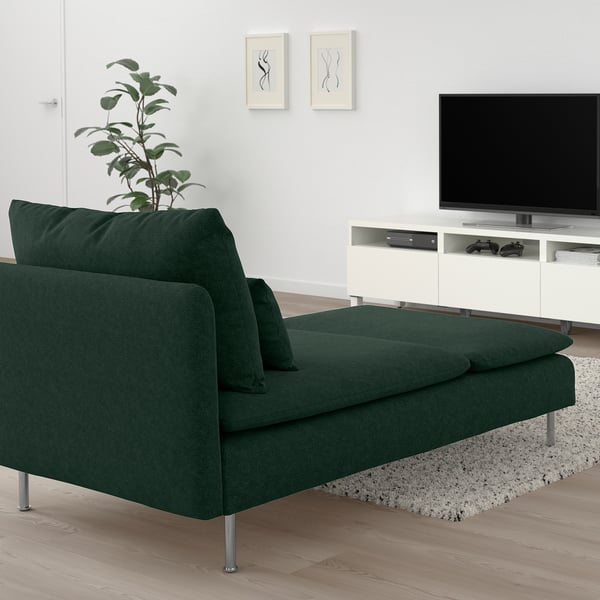 Salon moderne avec chaise longue verte, télévision et plante.