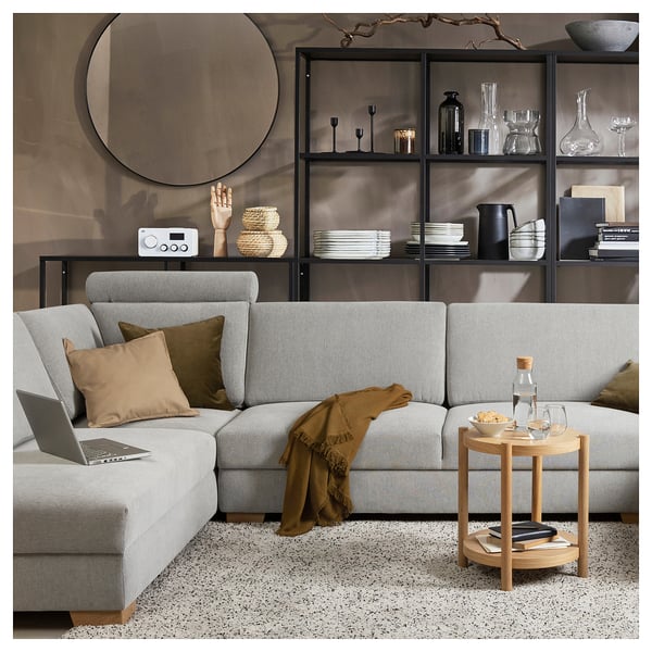 Salon moderne avec canapé SÖRVALLEN gris clair, table d’appoint en bois et étagères noires remplies d’objets de décoration.