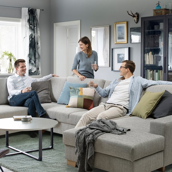 Trois bavardent sur le canapé SÖRVALLEN. Salon minimaliste avec art et table basse.