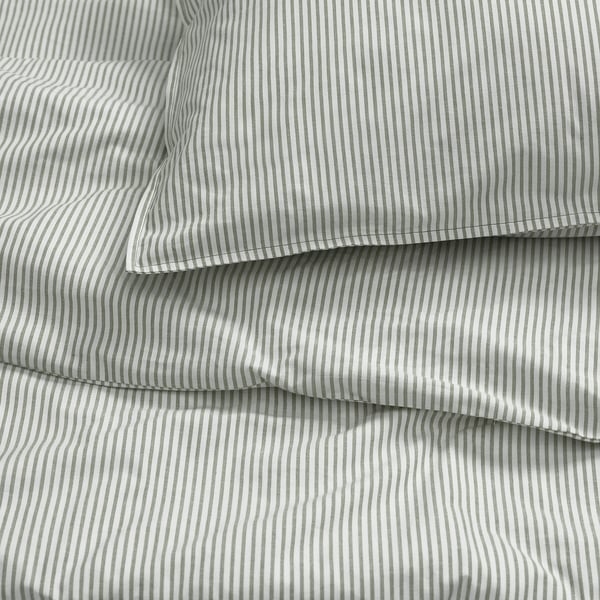 Gros plan de draps de lit à rayures grises soigneusement pliés, présentant une texture lisse et des coutures uniformes.