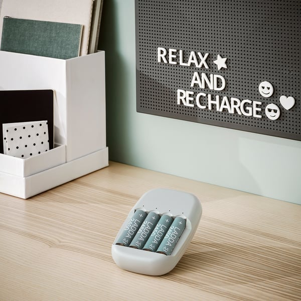 Chargeur et batteries sur le bureau, organisateur avec cahiers, tableau à lettres disant se détendre, se ressourcer, sourire.