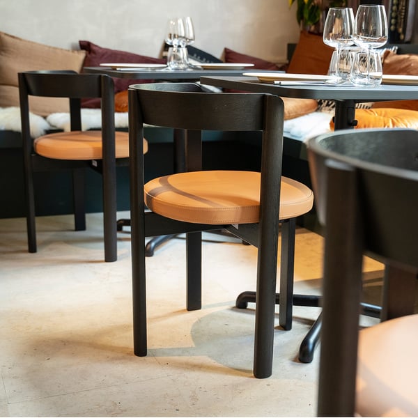 Table moderne noire en STENSELE avec sièges en cuir beige dans une salle à manger cosy.