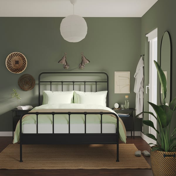 Chambre moderne vert foncé avec lit noir, literie blanche/verte et décoration simple.