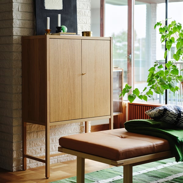 Banc élégant en cuir marron, ancré contre un meuble en bois clair, près d’une plante verdoyante.