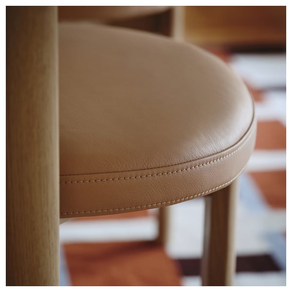 Gros plan d’un tabouret en cuir de haute qualité avec des coutures apparentes, mettant en valeur le savoir-faire et le confort de l’assise.