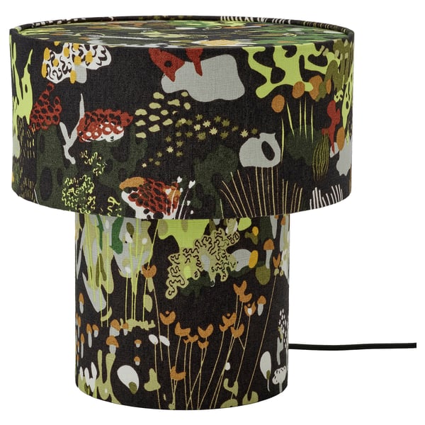Lampe de table STOCKHOLM 2025, noire avec des motifs verts, oranges, blancs, en tissu de lin, cylindrique, inspirée de la nature.