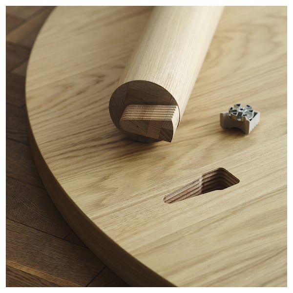Pièces d’assemblage de la table en bois : pied avec cheville et connecteur métallique, mettant en évidence la facilité du processus d’installation.