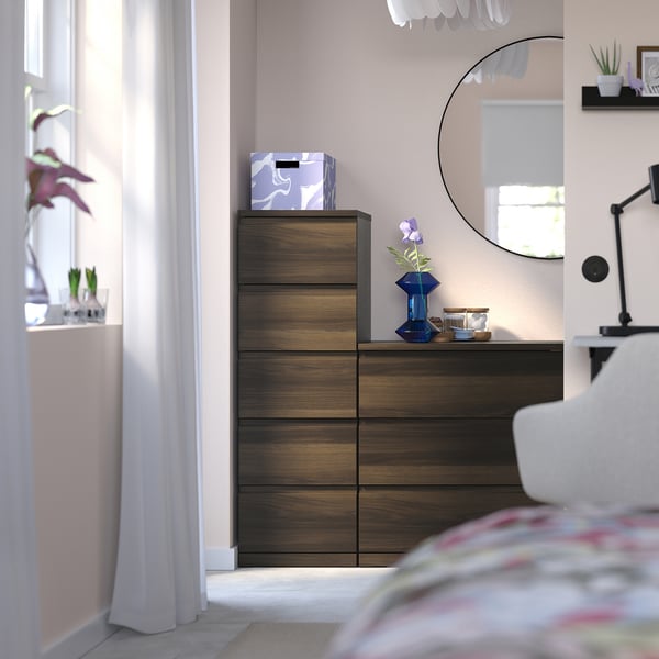 Coffre moderne en bois STORKLINTA avec tiroirs près de la fenêtre, lit, miroir. Marron foncé, murs pastel, design épuré.