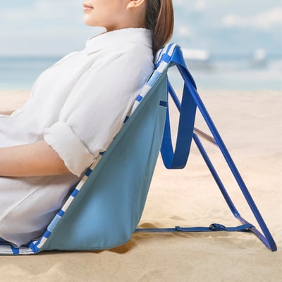 La personne se détend sur la chaise de plage bleue réglable STRANDÖN, mettant en valeur sa facilité d’installation et de rangement.