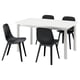 Une table à manger extensible IKEA STRANDTORP blanche avec quatre chaises noires. Les chaises ont des sièges incurvés et des pieds noirs.