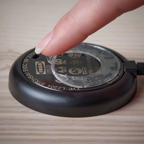 Pression à la main projecteur STRIMSÄV noir sur bois, alimenté par un tampon de gel.