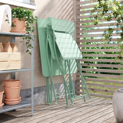 Trois chaises pliées en métal vert. Idéal pour les petits espaces.