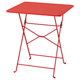 Une table en métal SUNDSÖ rouge vif et pliable avec un plateau carré et des pieds robustes à entretoises, idéale pour les petits espaces.