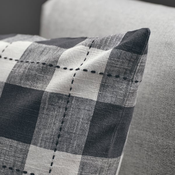 Noir et blanc, une housse de coussin à carreaux avec des coutures noires sur un canapé, mettant en valeur sa texture et son design de qualité.