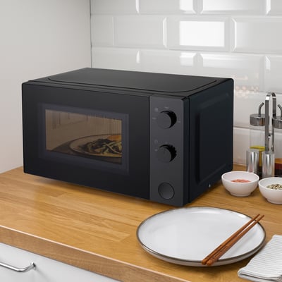 Micro-ondes TILLREDA noir sur comptoir en bois avec assiette et baguettes.
