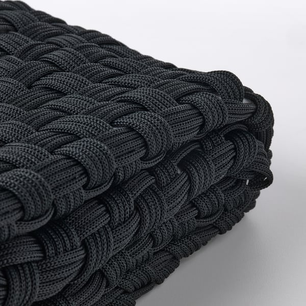 Housse de coussin en corde noire tressée, finement tissée, exposée sur un fond clair, mettant en valeur un savoir-faire de haute qualité.