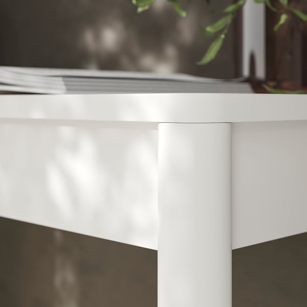 Gros plan d’un coin de bureau moderne, blanc brillant avec une finition lisse, montrant des lignes épurées et un design robuste.