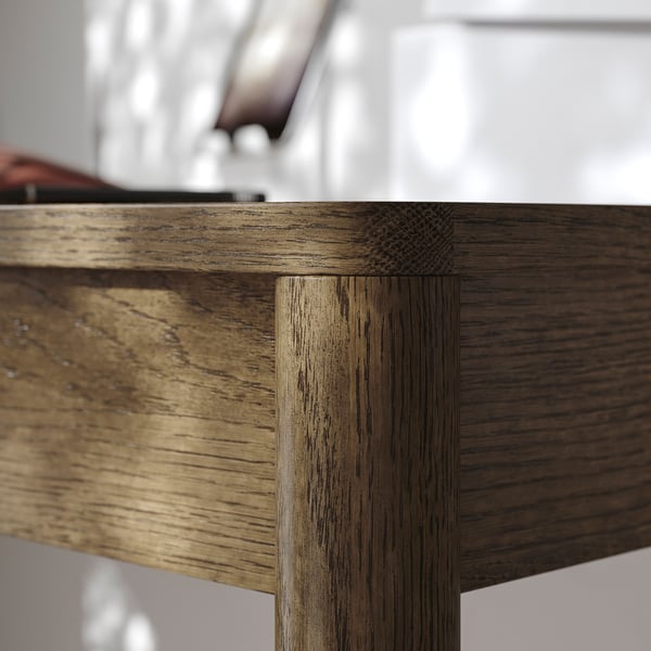 Gros plan d’un coin de table en bois, mettant en valeur la texture détaillée du placage de chêne et la conception précise de la menuiserie.