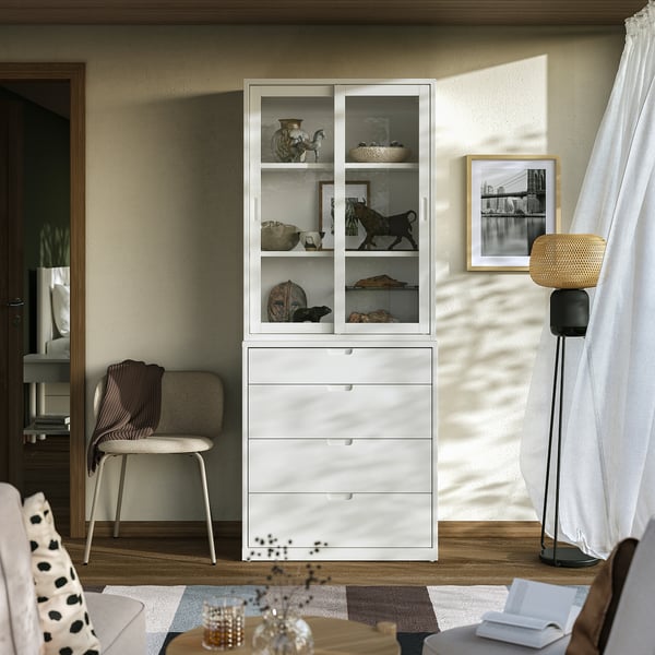 Salon moderne avec armoire et chaise TONSTAD blanches, objets de décoration, livres, lampe et rideau de fenêtre.