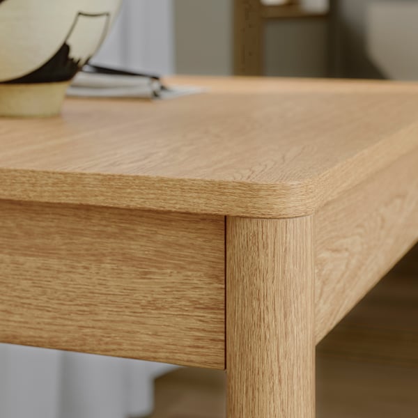 Gros plan d’une table en bois bien conçue aux bords lisses et arrondis, mettant en valeur sa finition en chêne naturel et sa construction robuste.