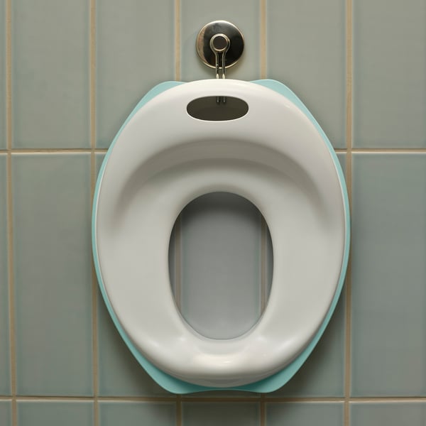 Un siège de toilette pour enfants blanc et turquoise, façonné pour le confort, fixé à un mur carrelé.