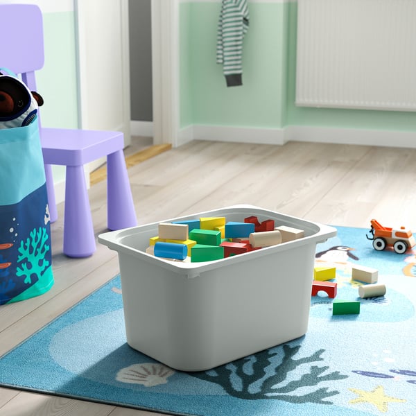 Une boîte de rangement en plastique blanc remplie de jouets colorés sur un tapis bleu, idéale pour ranger les articles des enfants.